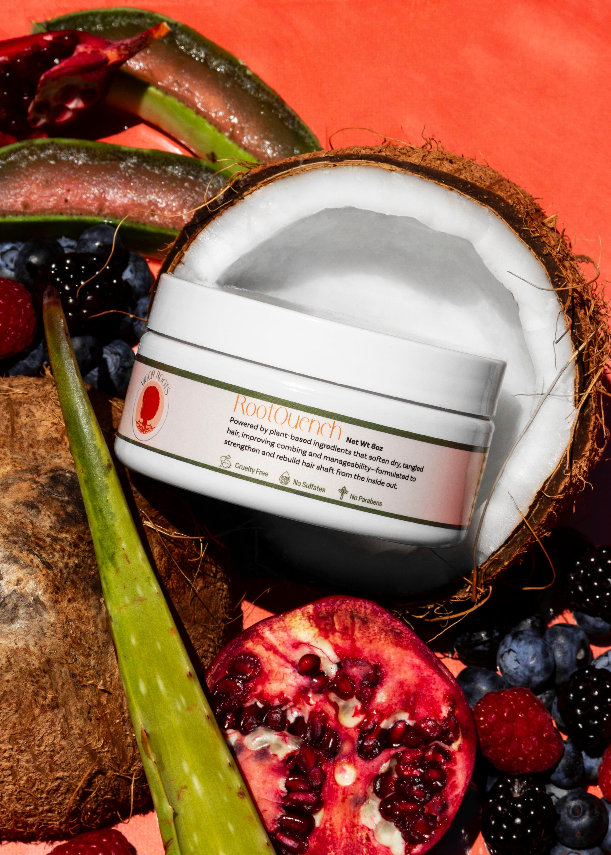 A jar of RootQuench, Vigor Roots' moisturizing conditioner is posed with pomegranate, coconut, aloe vera, & fresh berries- just a few of the all-natural, food-grade ingredients included in the formula.