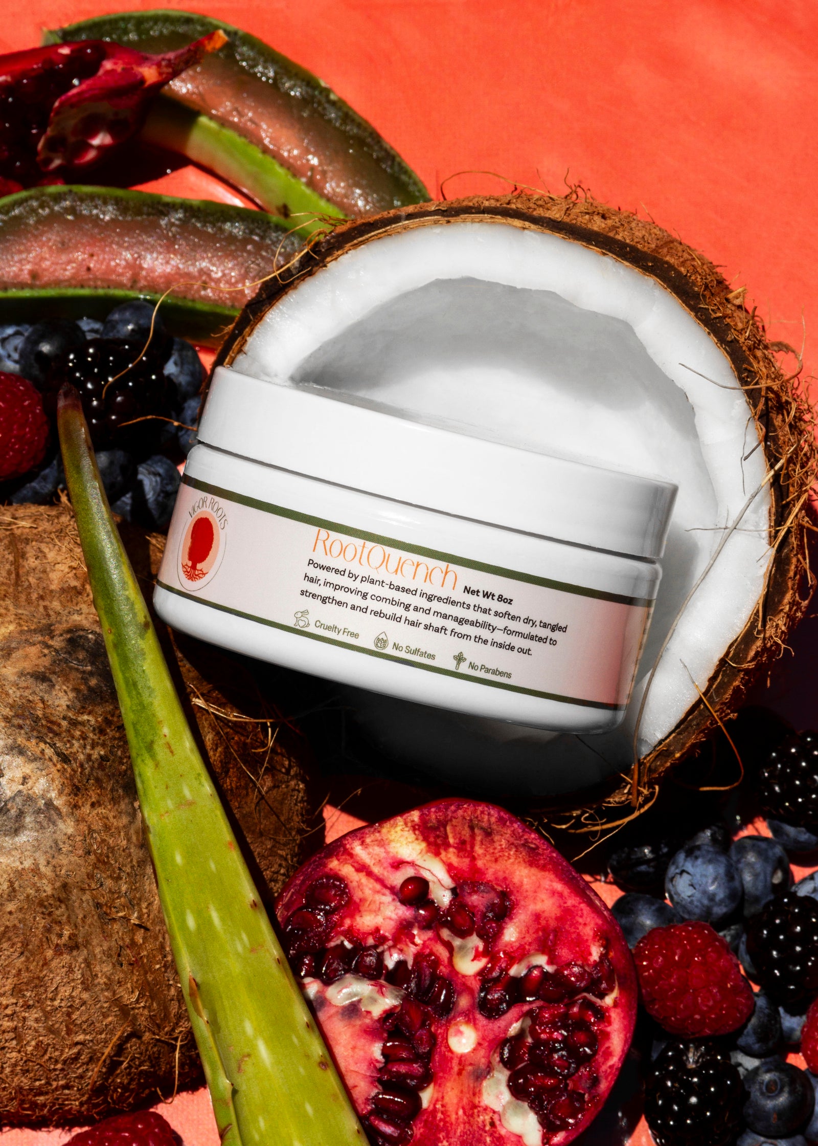A jar of RootQuench, Vigor Roots' moisturizing conditioner is posed with pomegranate, coconut, aloe vera, & fresh berries- just a few of the all-natural, food-grade ingredients included in the formula. 